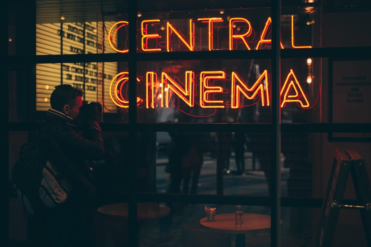 An image of a red neon sign that says 'Central Cinema' at the entrance of a building.